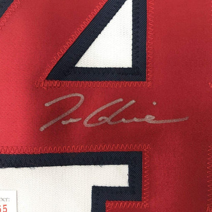 Close-up of red fabric with black and white geometric design and cursive signature in gray stitching.