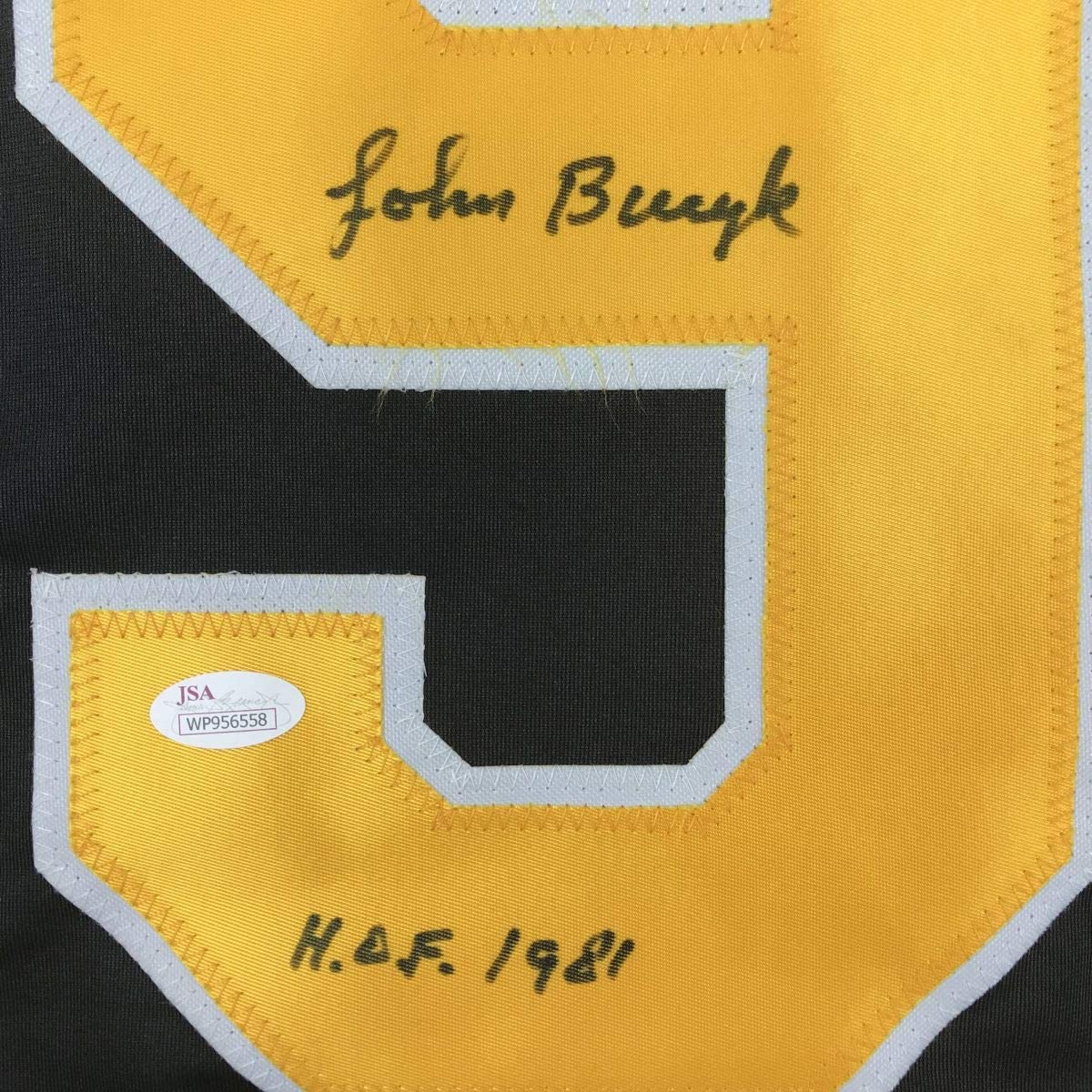 Close-up of yellow jersey shoulder showing "John Buryk" autograph, "H.O.F. / 1981" text, and JSA authentication label.