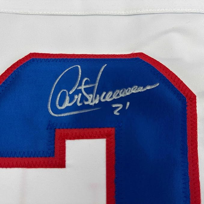 Close-up of autographed blue and red hockey jersey showing silver signature on blue fabric panel with red trim.