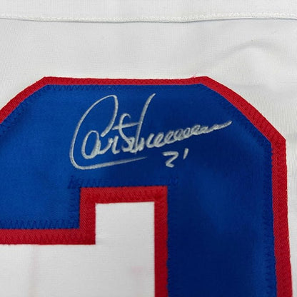 Close-up of autographed blue and red hockey jersey showing silver signature on blue fabric panel with red trim.
