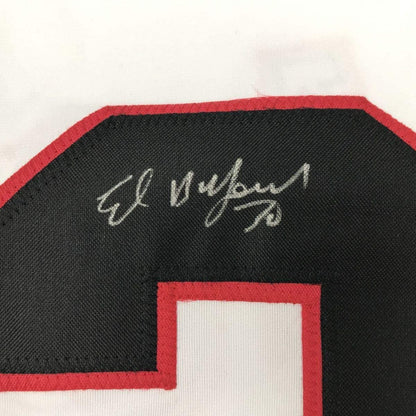 Close-up of handwritten silver signature on black fabric with red trim of hockey jersey.