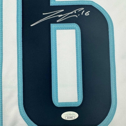 Close-up of dark navy jersey back showing white rectangular nameplate with turquoise binding and handwritten signature dated 2016.