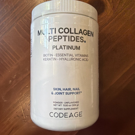 White plastic jar of Codeage Multi Collagen Peptides Platinum powder supplement on wood surface, front label visible.