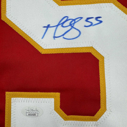 Close-up of signed Calgary Flames jersey showing blue autograph and JSA authentication sticker on white and red fabric with gold trim.