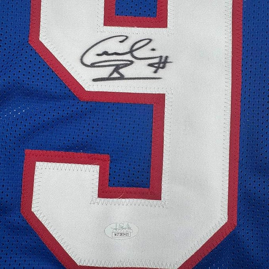 Close-up of autographed blue and red football jersey showing signed white nameplate panel with handwritten signature and JSA authentication hologram.