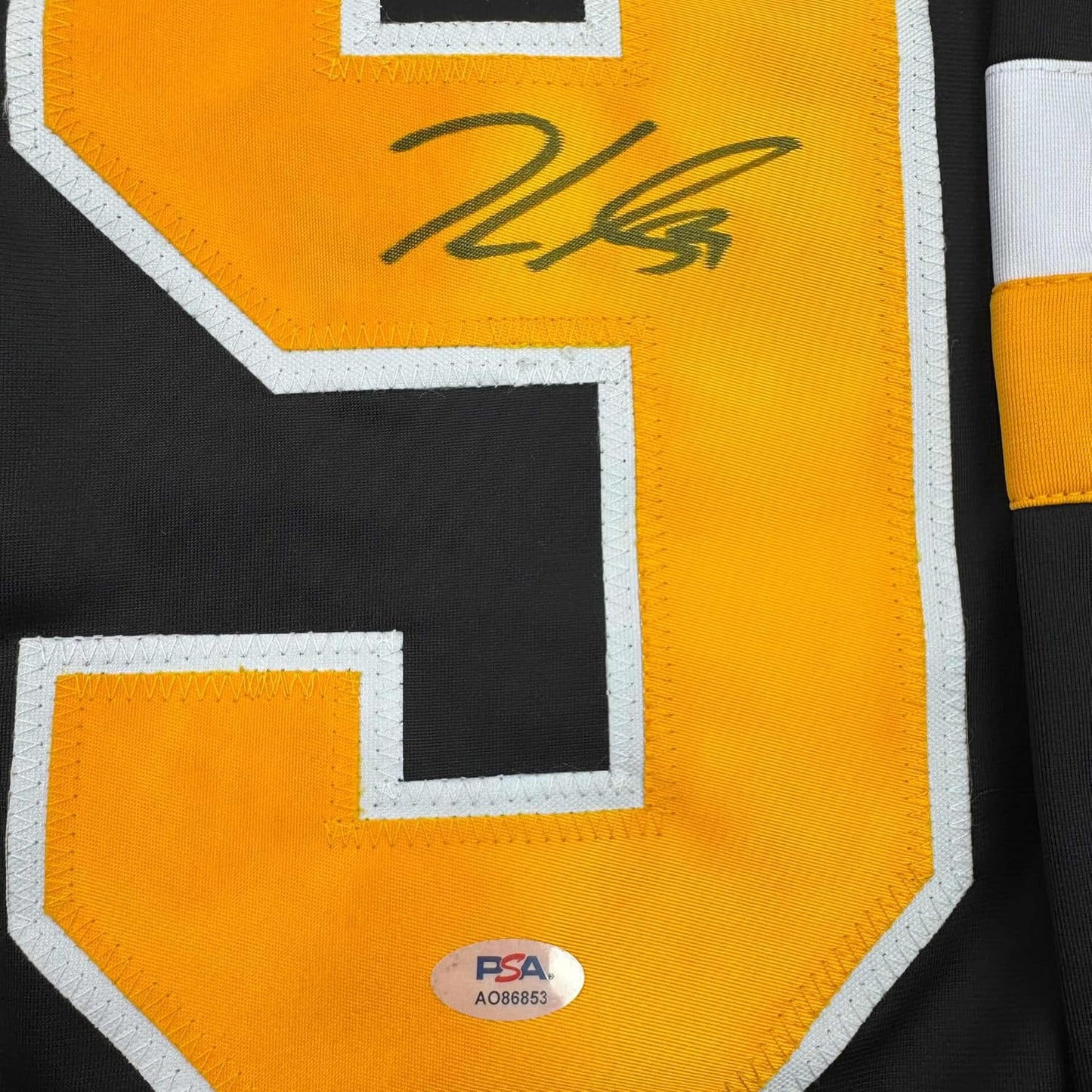 Close-up of signed yellow hockey jersey number 24 with white trim and PSA authentication sticker.