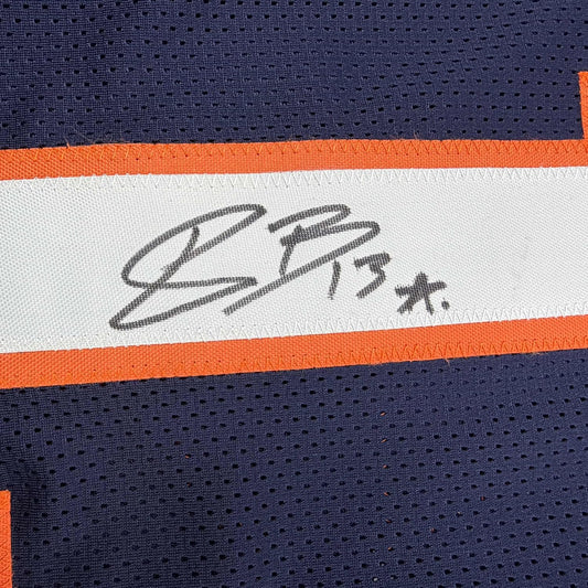 Close-up of autographed white stripe on navy and orange Denver Broncos football jersey showing handwritten signature.
