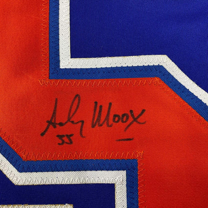 Close-up of handwritten signature on red fabric panel of Edmonton Oilers hockey jersey with blue and white striping.