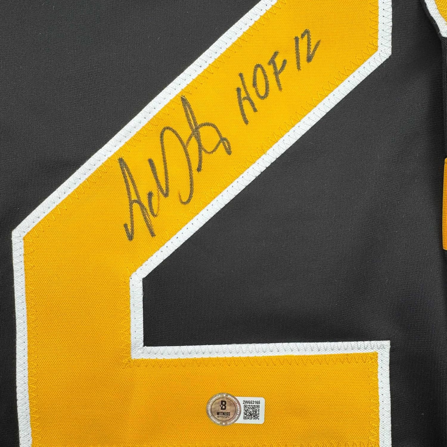 Close-up of yellow and black hockey jersey shoulder showing "Adam Oates HOF 12" autograph and Beckett authentication hologram.