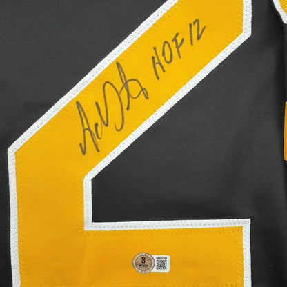 Close-up of yellow and black hockey jersey shoulder showing "Adam Oates HOF 12" autograph and Beckett authentication hologram.
