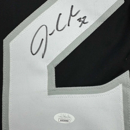 Close-up of handwritten signature on white fabric label with JSA authentication sticker visible below.