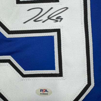 Close-up of autographed blue and white hockey jersey showing handwritten signature and PSA authentication sticker.