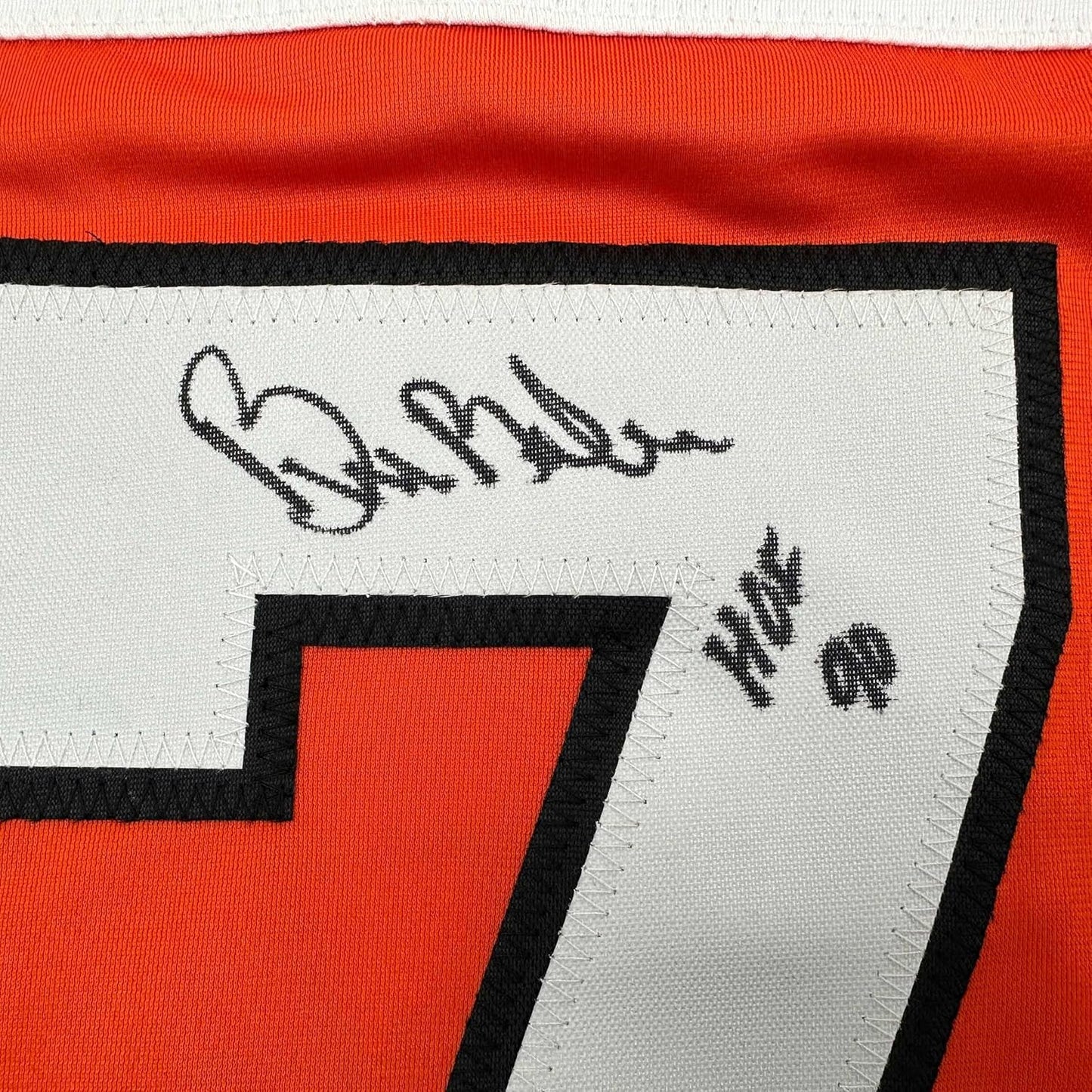 Close-up of autographed orange and black Philadelphia hockey jersey with signature and "HOF 90" printed on white panel.
