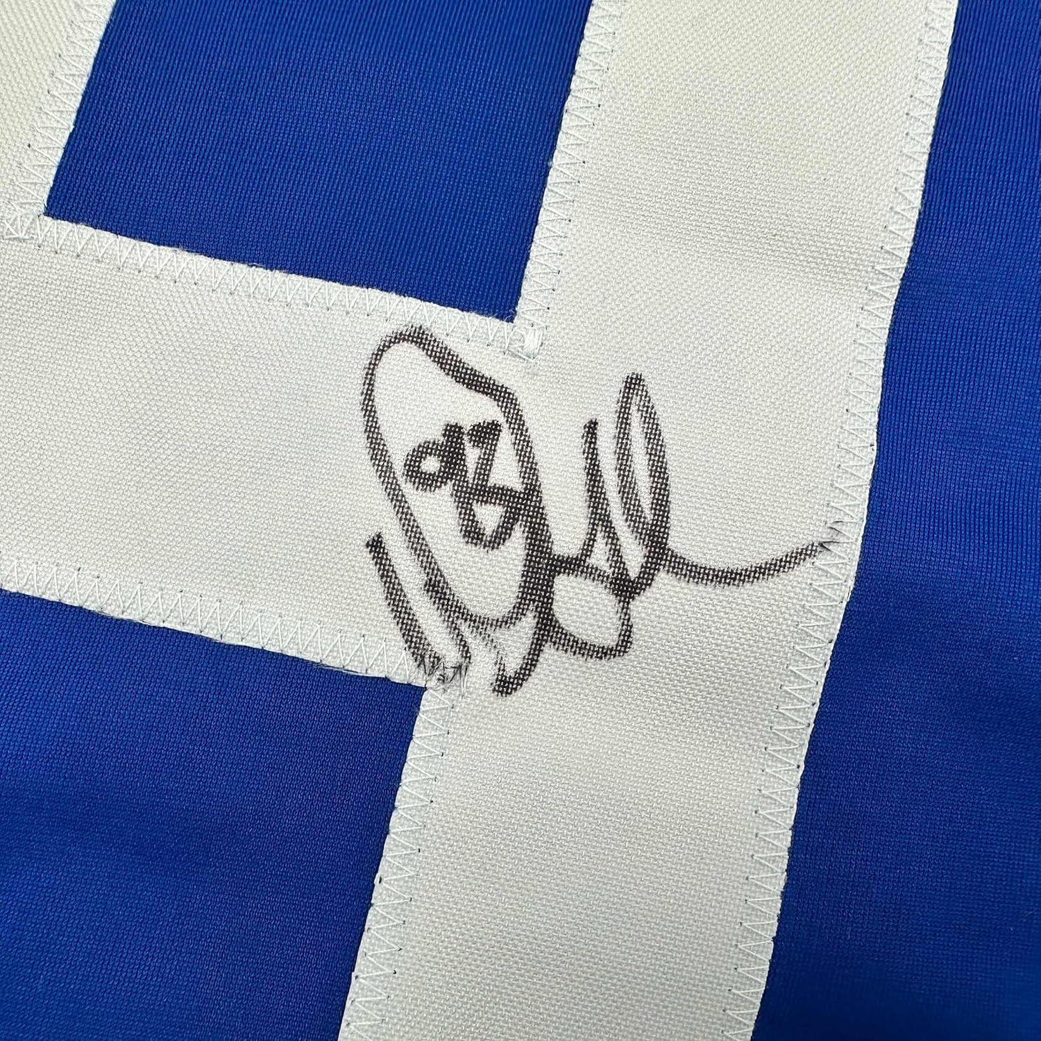 Close-up of handwritten autograph in black ink on white stripe of blue and white striped jersey fabric.