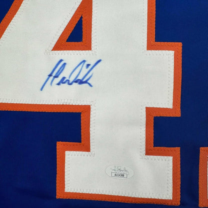 Close-up of blue autographed signature and JSA authentication sticker on white jersey panel with orange and blue trim.