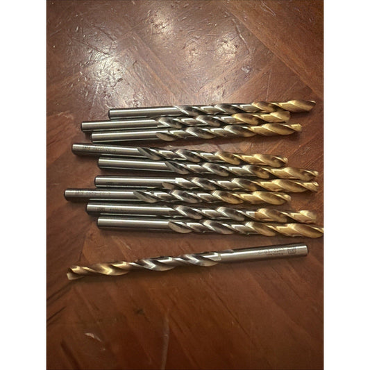 Ten TiN-coated carbide drill bits arranged in rows on brown fabric, displaying gold and silver metallic finishes.