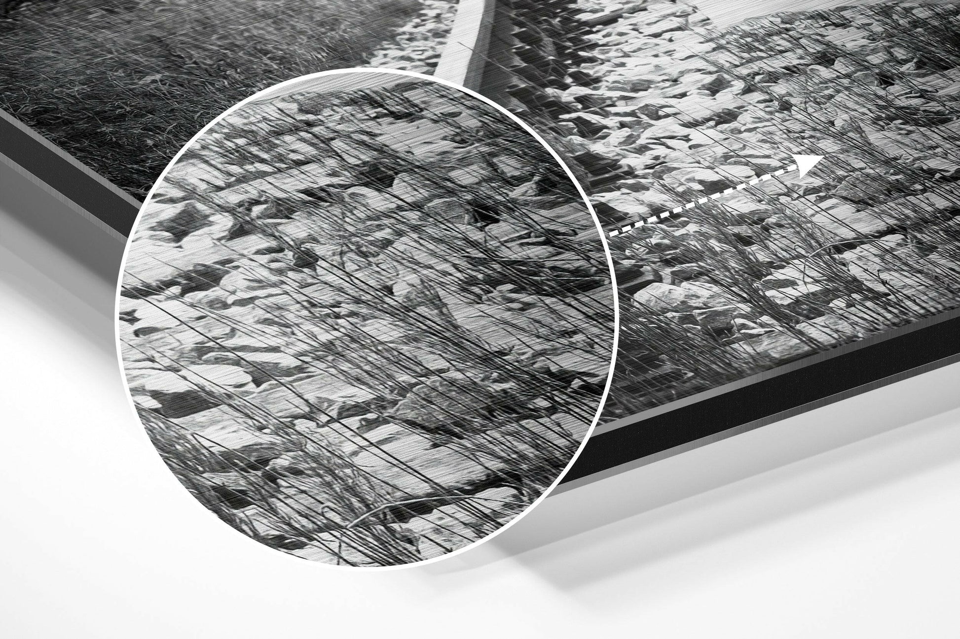 Close-up detail of brushed aluminum dibond wall art showing circular mirror reflection of bare tree branches in black and white.