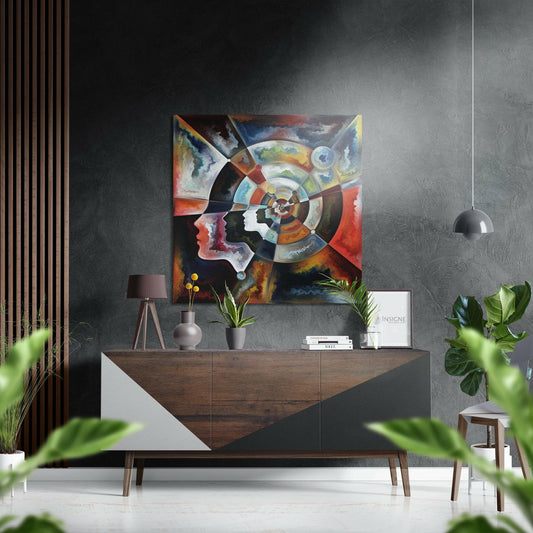 Colorful abstract artwork featuring two overlapping profile faces and concentric circular patterns displayed above a wooden console table in a modern interior setting.
