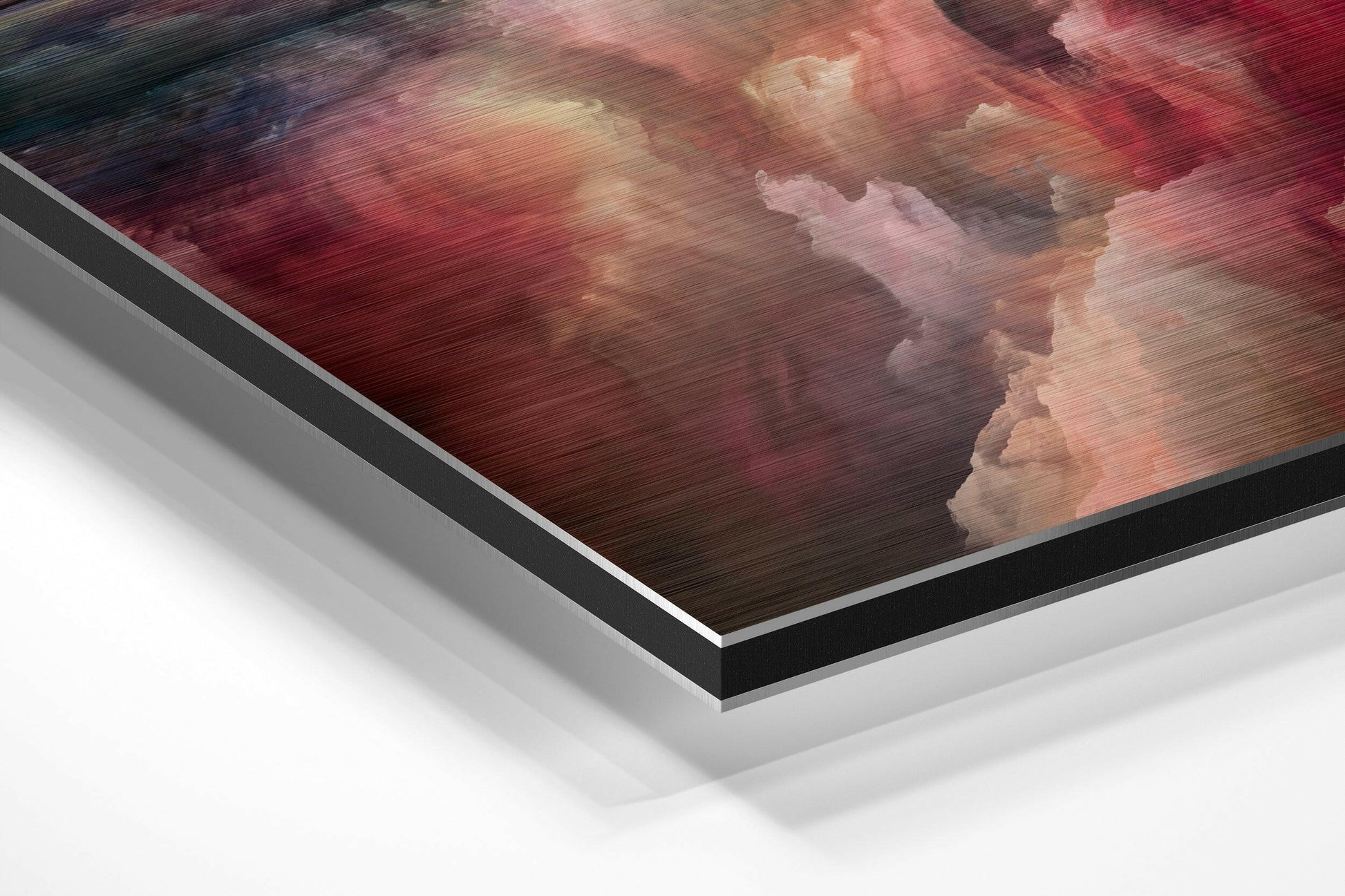 Angled perspective view of brushed aluminum Dibond wall art featuring red and pink clouds with white highlights and visible layered edge construction.