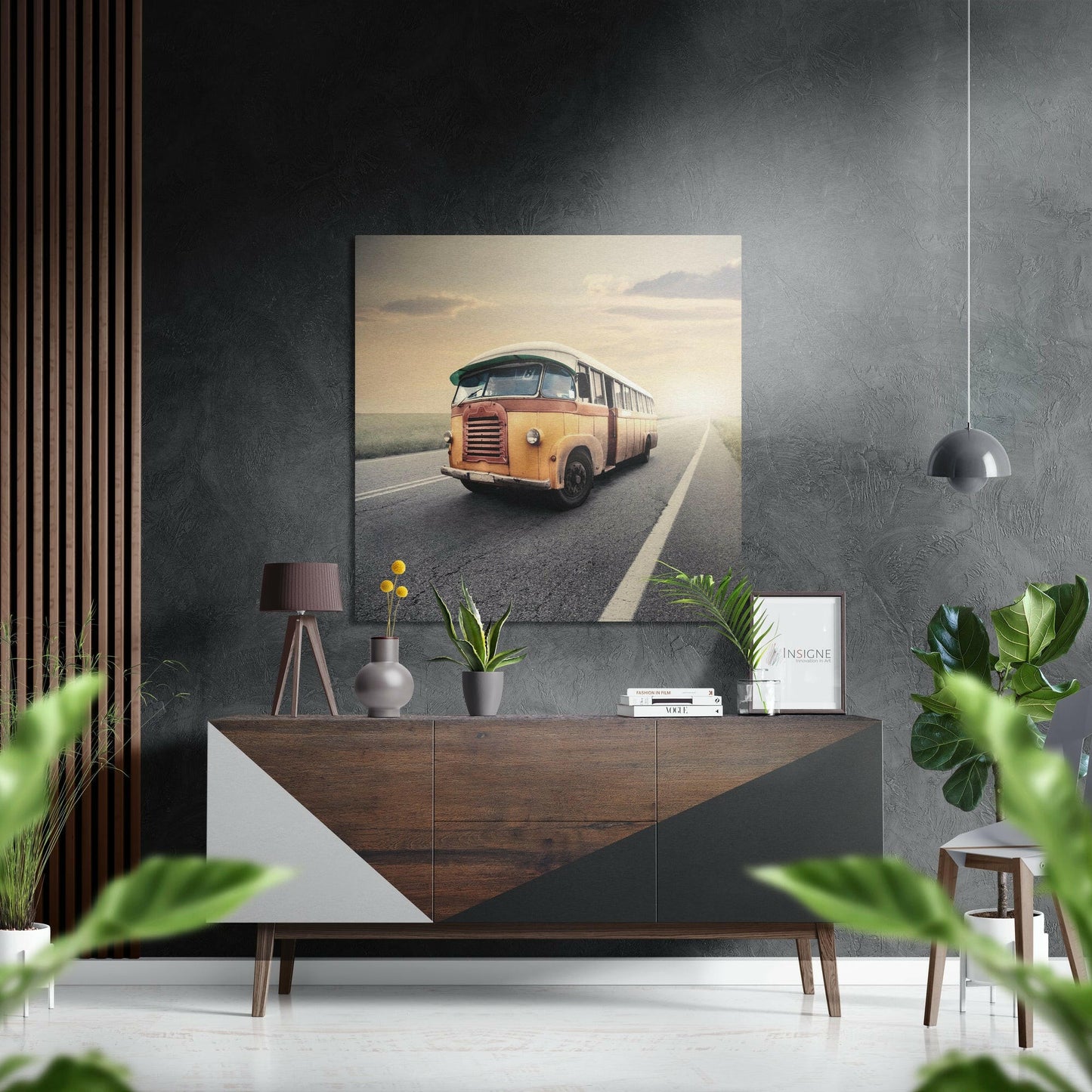 Vintage orange bus traveling down a sunlit highway with white road markings, displayed as wall art above a wooden dresser in a modern interior.
