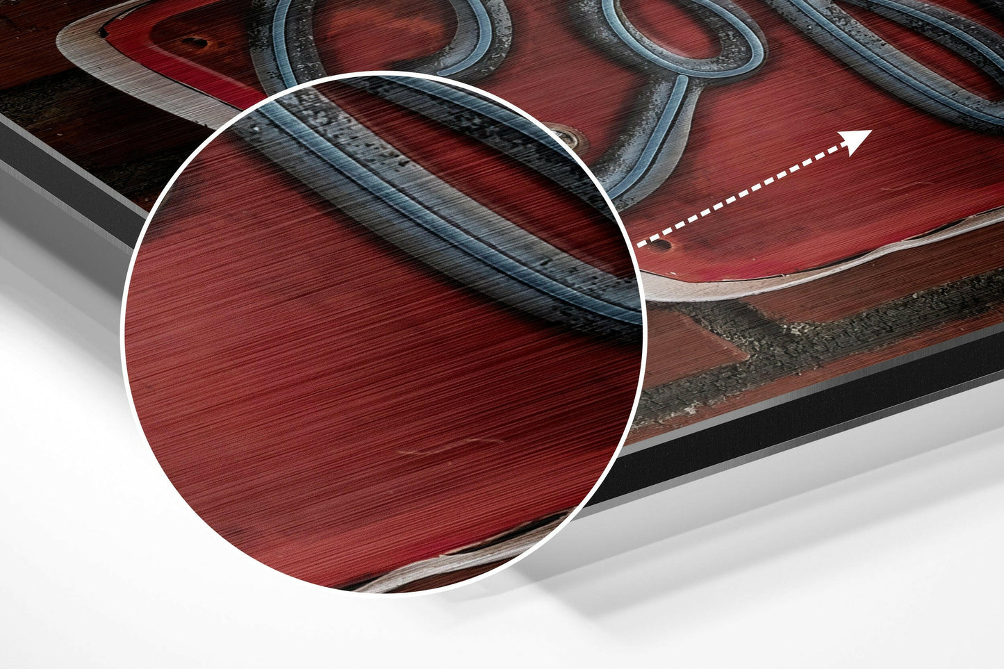 Close-up detail of brushed red aluminum surface with dark metal straps and white circular magnification overlay, angled product view.