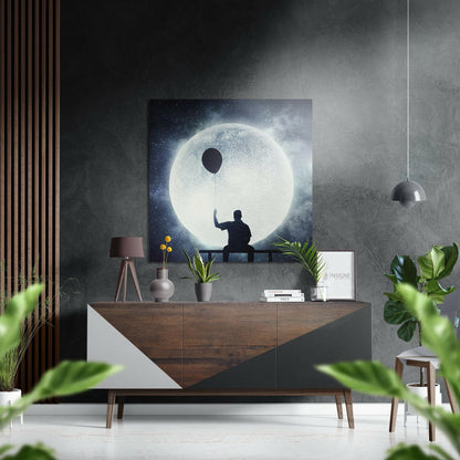 Surreal moon artwork displayed on textured gray wall above wooden dresser with potted plants and pendant lamp.