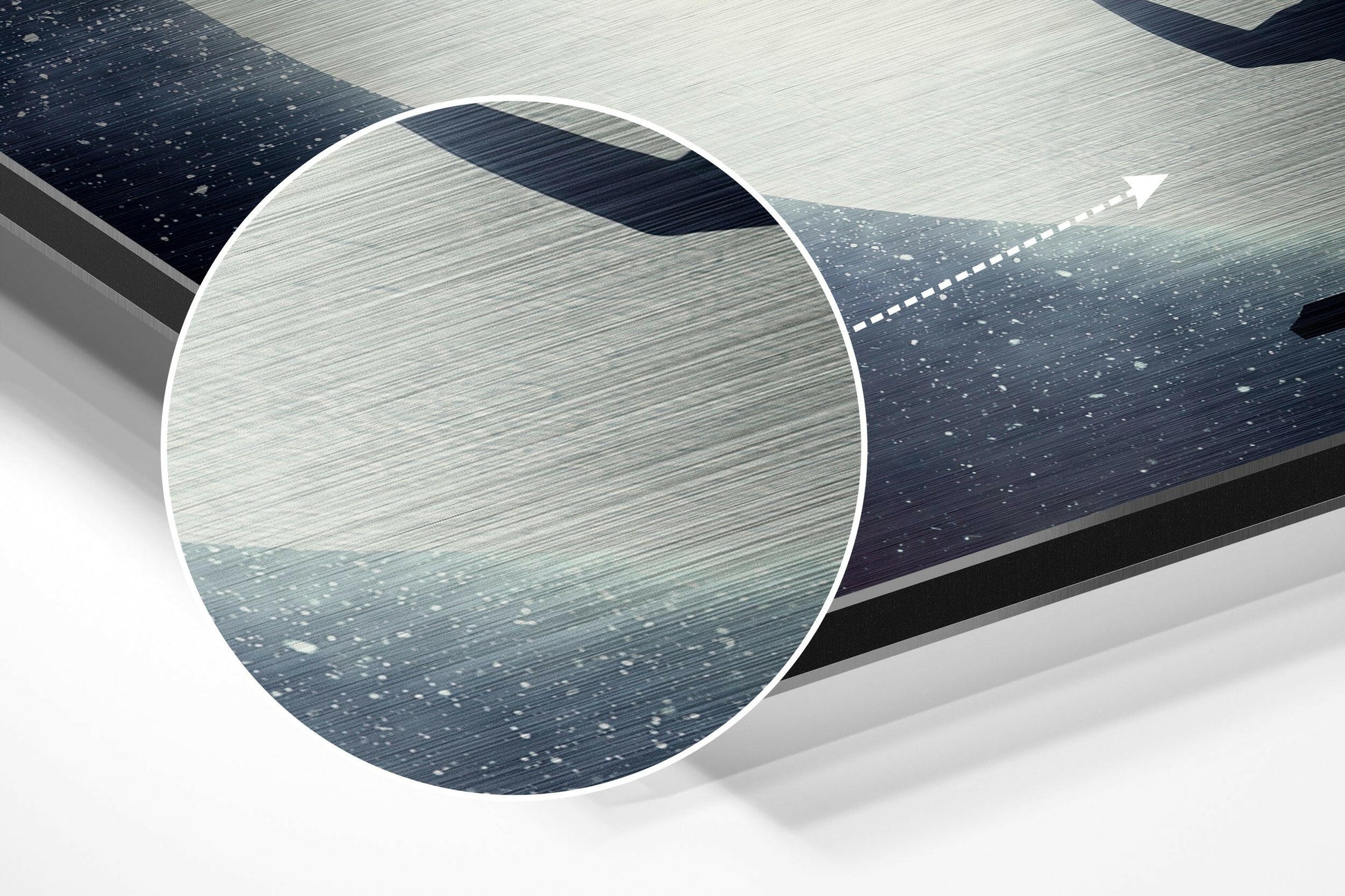 Close-up detail shot of brushed aluminum surface showing horizontal texture and light reflection with directional arrow overlay on dark and light toned panels.