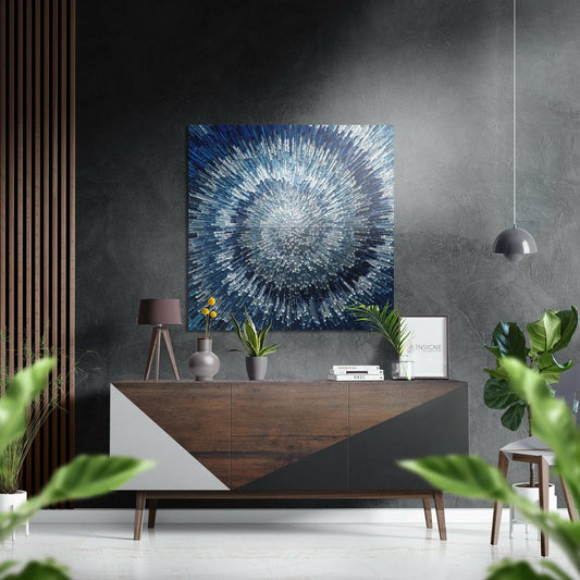 Modern living room interior with blue and silver radial burst wall art hanging above wooden dresser with decorative objects.