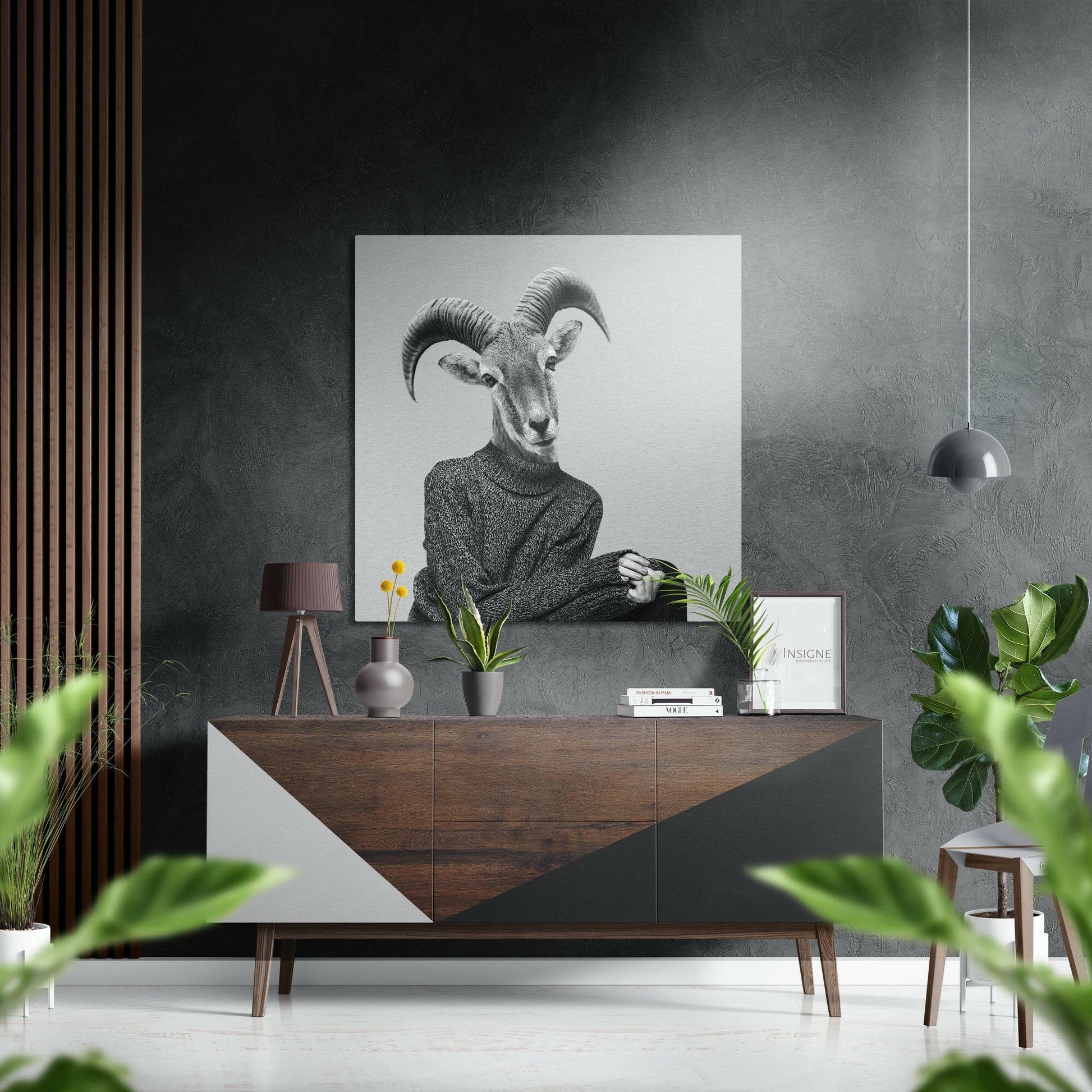 Black and white goat-headed figure in sweater displayed above wooden dresser in modern interior setting with plants and accessories.