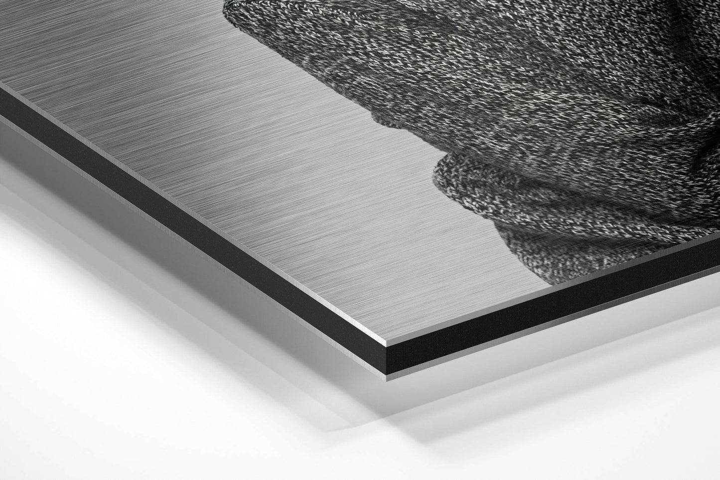 Close-up angled view of brushed aluminum Dibond panel with black textured goat head design in upper right corner against white background.