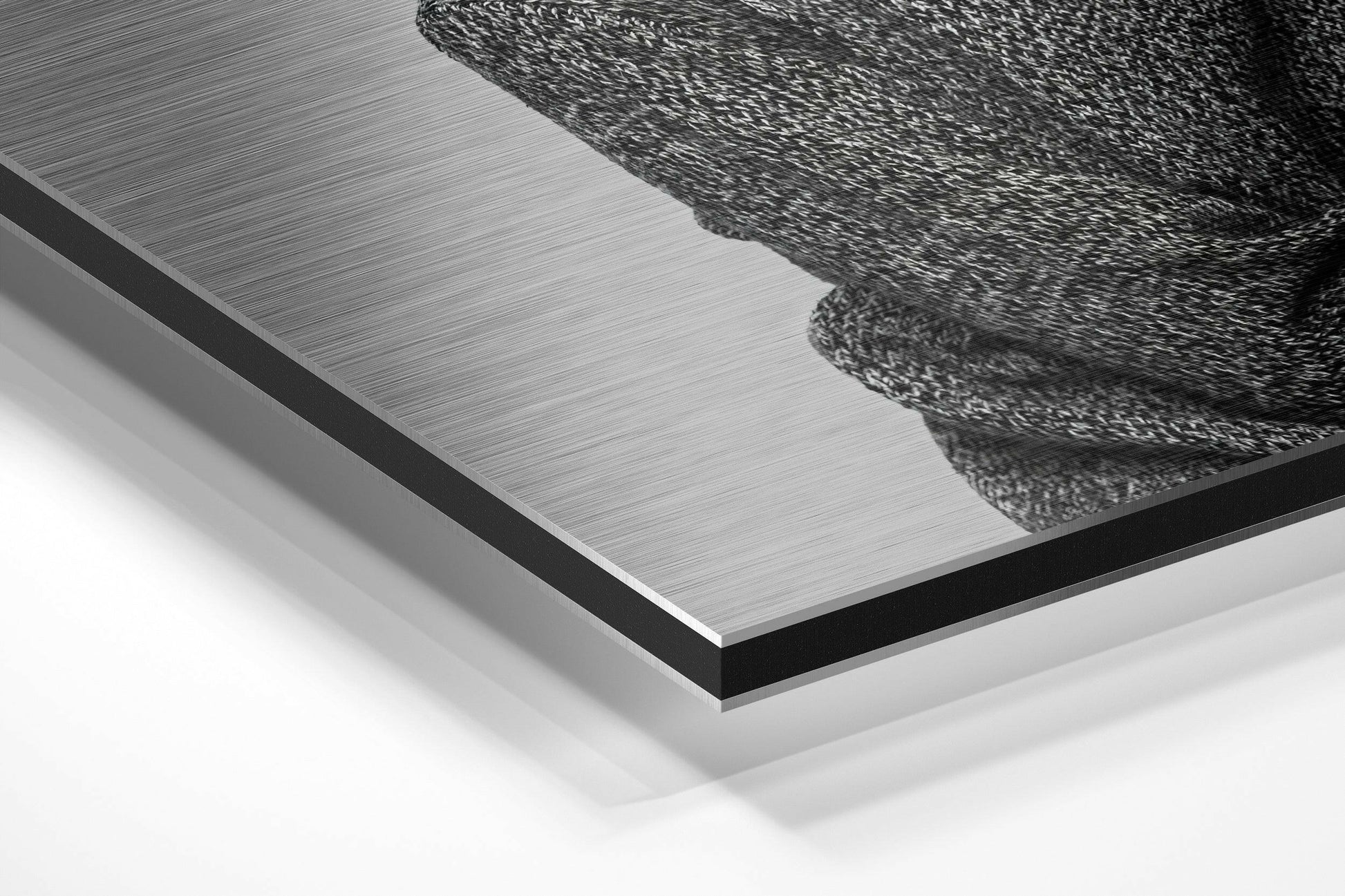 Close-up angled view of brushed aluminum Dibond panel with black textured goat head design in upper right corner against white background.