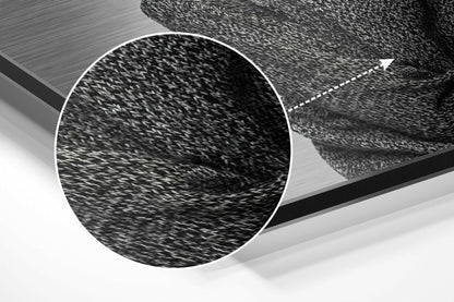 Close-up detail of brushed aluminum surface texture with circular white border outline and directional arrow on textured dark material.