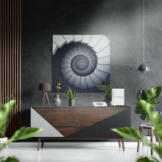 Modern interior with spiral staircase wall art mounted above wooden dresser with potted plants and pendant lamp.