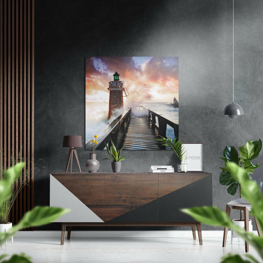 Lighthouse Brushed Aluminium Dibond Wall Art displayed above a wooden dresser in a modern interior, showing a dramatic seascape with a red lighthouse, wooden pier, and sunset sky.
