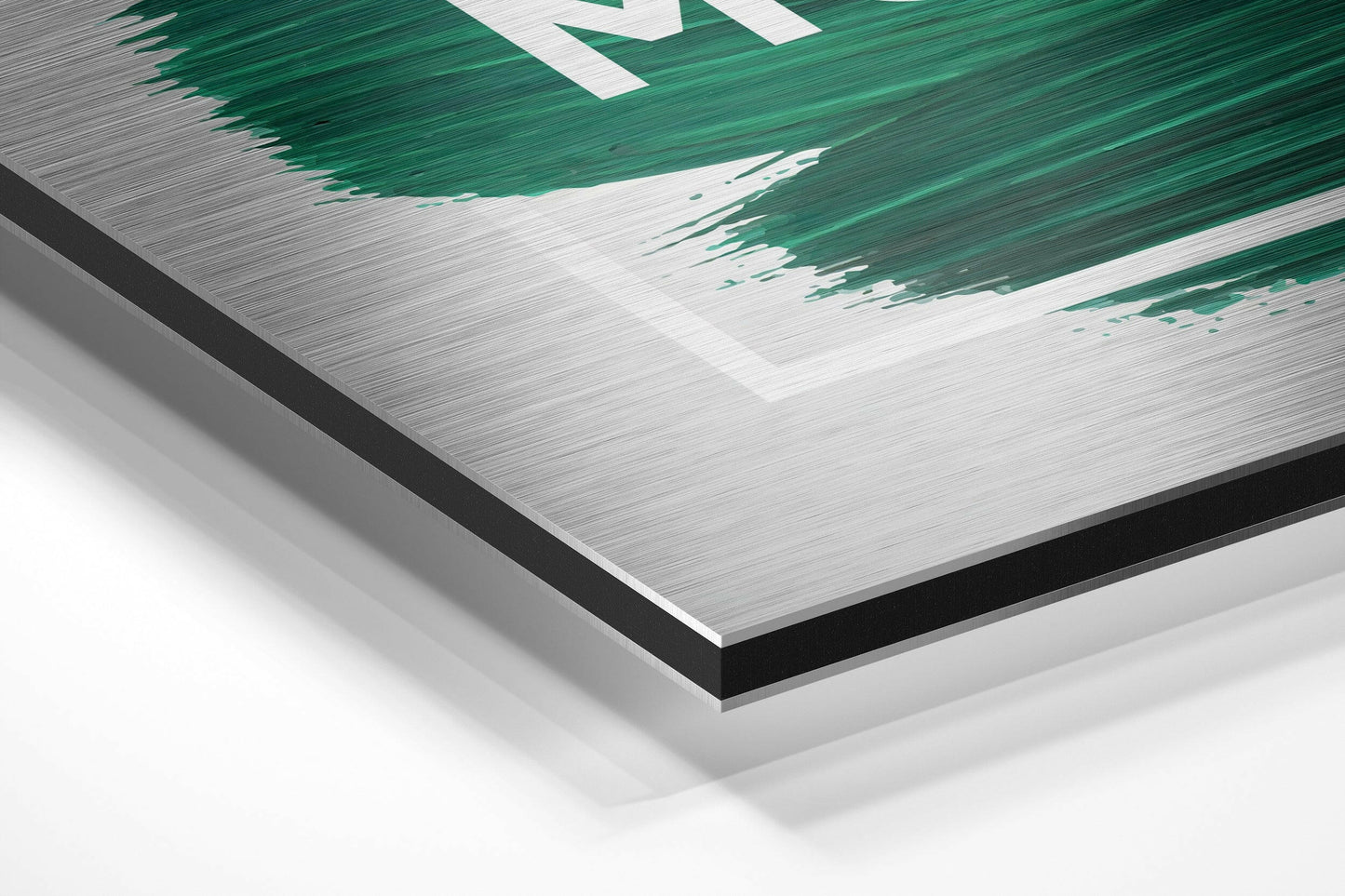 Close-up angled view of brushed aluminum dibond panel edge showing layered construction with white and black backing layers beneath green and white printed surface design.