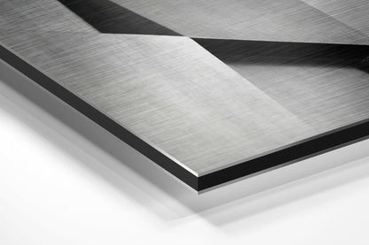 Close-up angled view of layered brushed aluminum and black dibond panels showing geometric folded surfaces with directional texture.