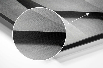 Close-up of brushed aluminum circular panel showing metallic grey surface texture with directional arrow indicator on geometric background.