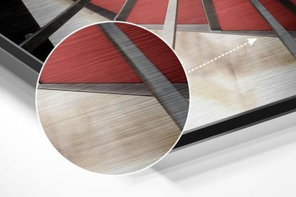 Close-up circular magnification showing layered brushed aluminum panels in red, beige, and gray with shadow detail and directional arrow marking.