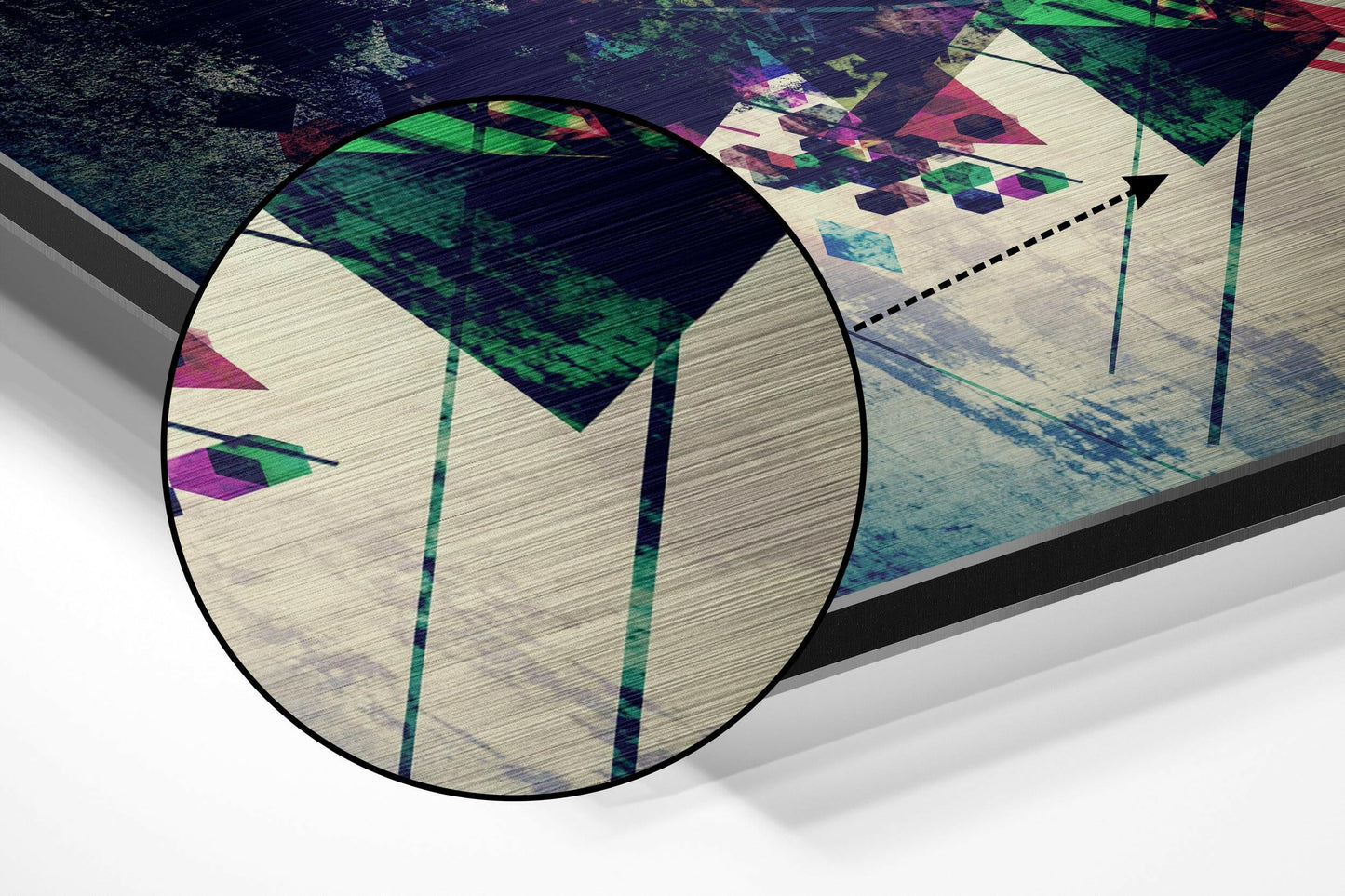 Close-up detail shot of brushed aluminium surface showing colorful geometric patterns with green, pink, and blue shapes under magnified circular lens.
