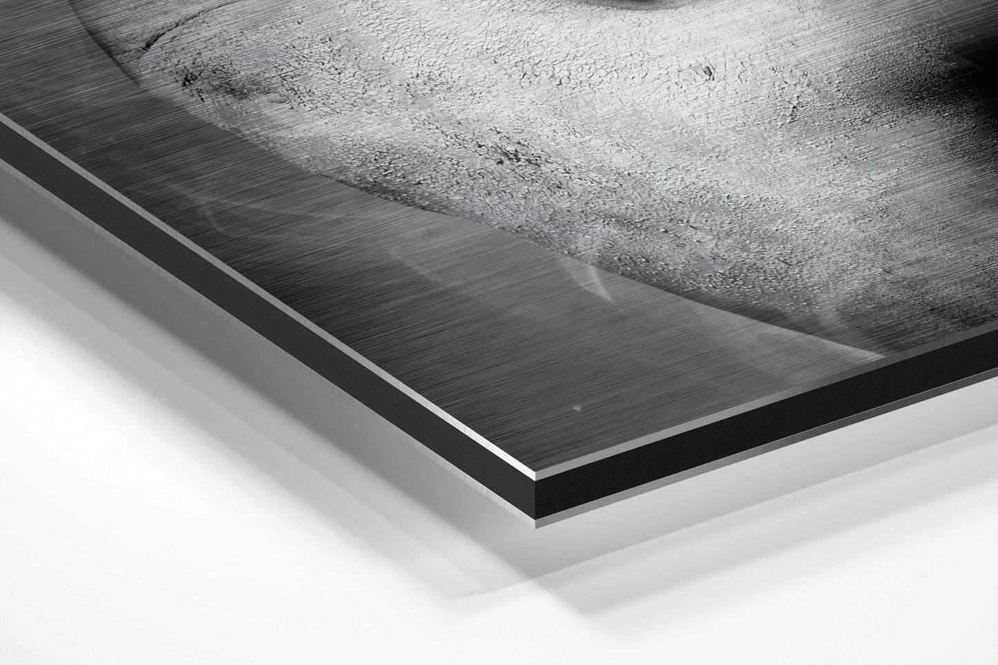 Close-up angled view of brushed aluminum Dibond panel edge showing layered black and white material construction and brushed metal surface texture.