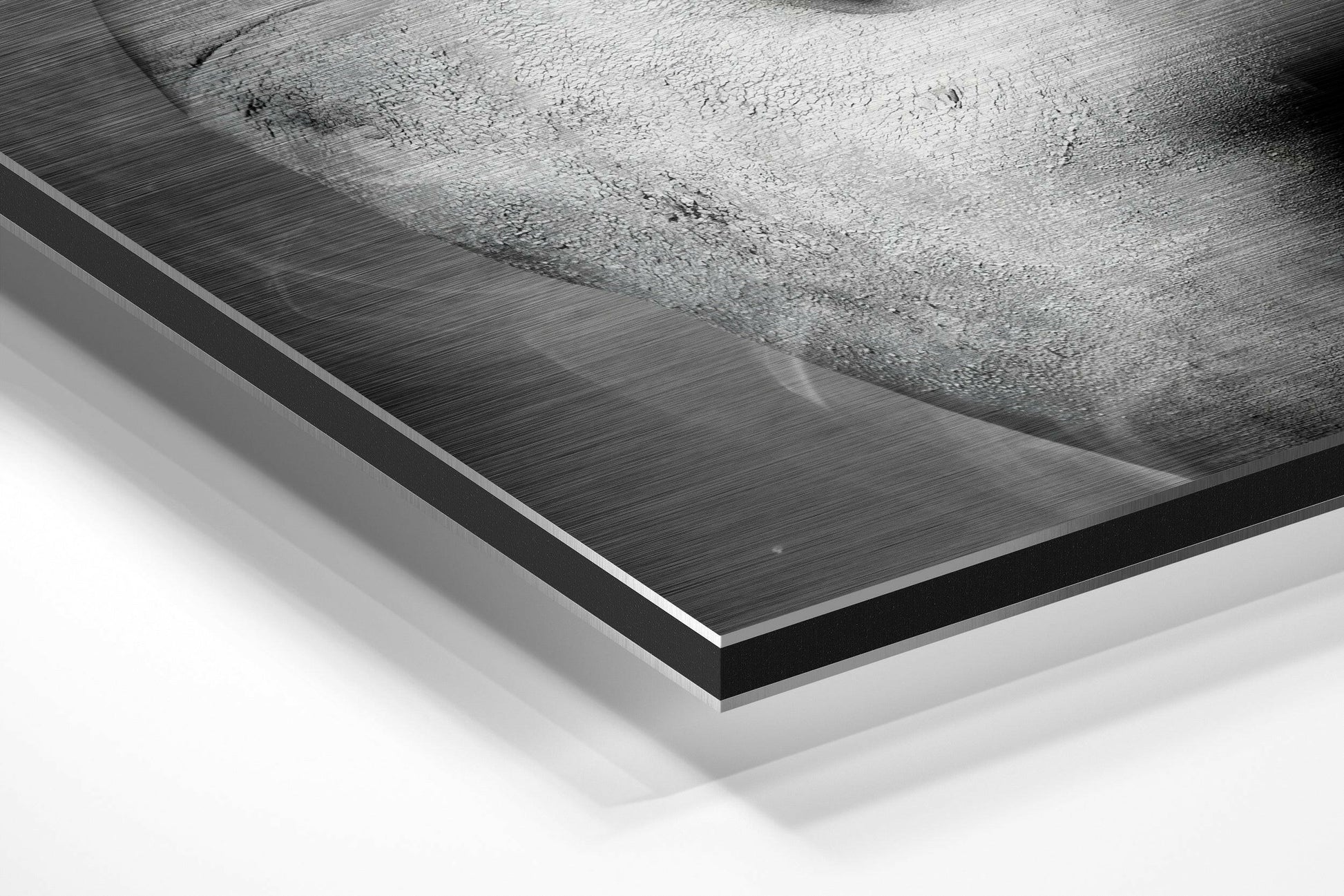 Close-up angled view of brushed aluminum Dibond panel edge showing layered black and white material construction and brushed metal surface texture.