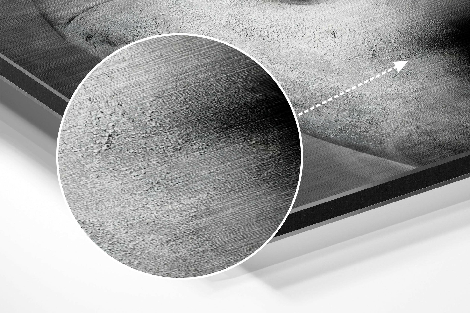 Close-up detail shot of brushed aluminium surface texture with white circular frame outline and directional arrow on gray concrete background.