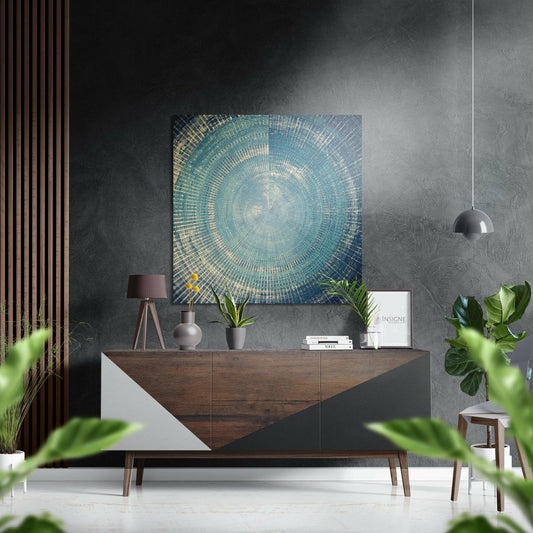 Turquoise and gold concentric circular pattern artwork displayed above mid-century wooden dresser in modern interior setting.
