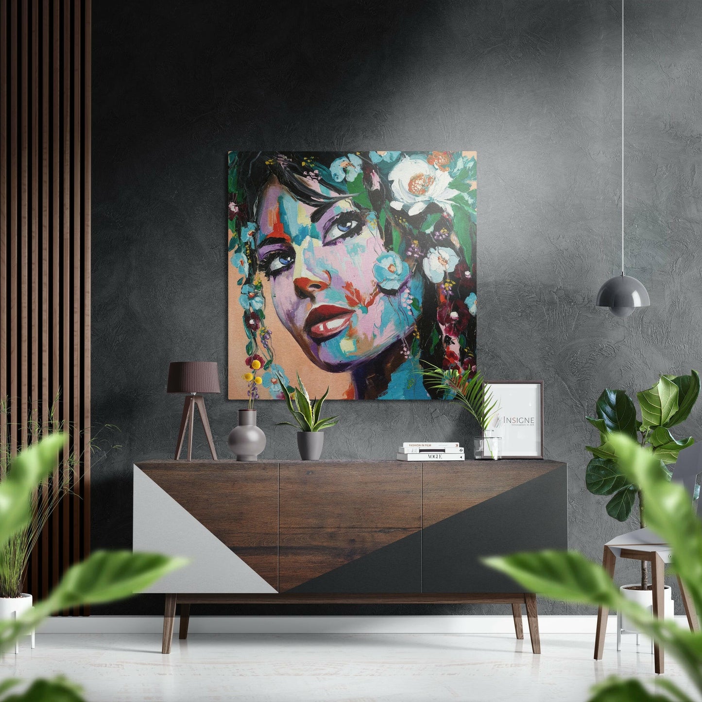 Colorful pop art portrait of a woman's face with floral elements displayed above a wooden dresser in a modern interior setting.