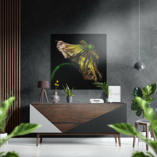 Wilting green flower artwork displayed on dark wall above wooden sideboard in modern living room setting with plants and decor.