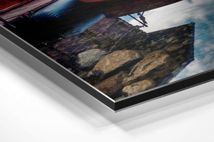 Angled perspective view of brushed aluminium Dibond wall art displaying a dynamic water sports scene with rocky shoreline and blue sky.