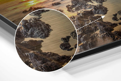 Close-up detail of brushed aluminium Dibond wall art showing aerial landscape with fields, rocks, and trees in earth tones, with magnified circular inset highlighting texture.
