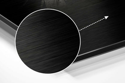 Close-up angled view of brushed aluminum Dibond wall art featuring a large black circle with white outline and directional arrow on textured background.
