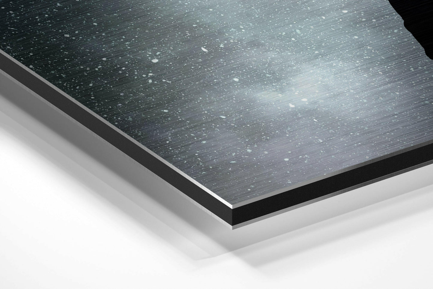 Angled close-up of layered brushed aluminum Dibond panel showing dark textured surface with white backing layers and black edge trim.