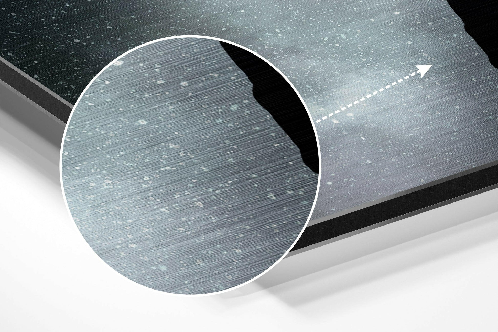 Close-up circular detail showing brushed aluminum surface texture with white directional arrow on grey speckled background.